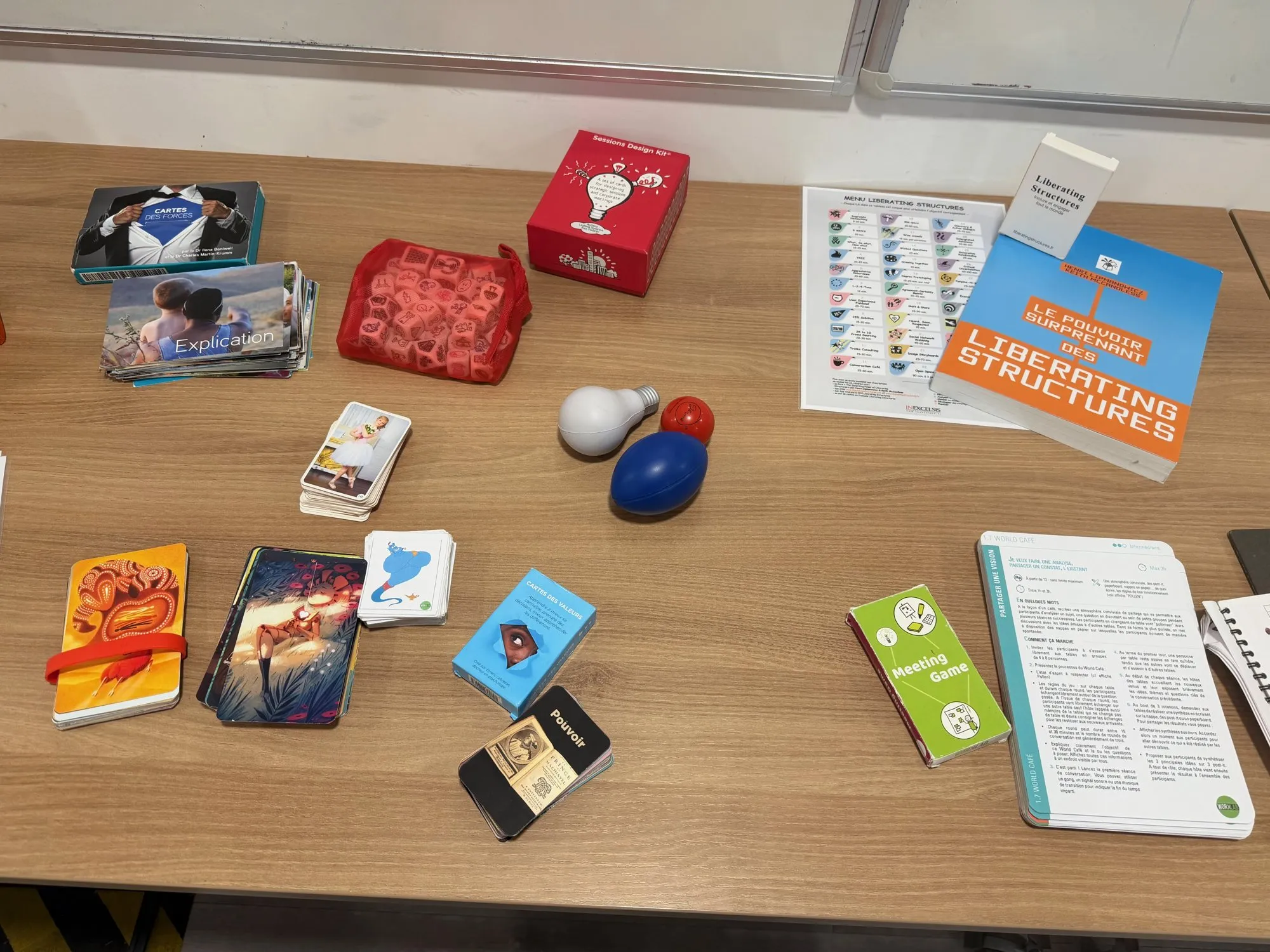 Table couverte de jeux de cartes, de cartes images et d’un livre sur les Liberating Structures